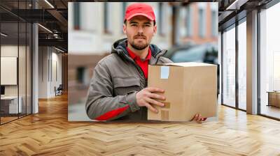 Delivery man holding cardboard box for delivery. Courier holding cardboard box for delivery. Man holding heavy cardboard box. Wall mural