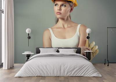 Attractive woman engineer in safety helmet holding gloves Wall mural