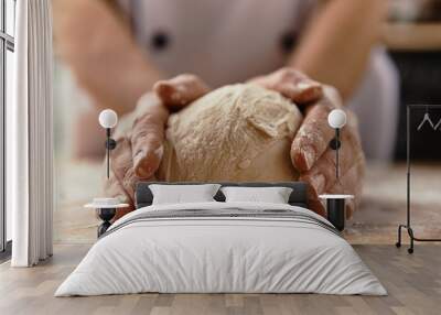 Close-up of chef hands kneading raw bread dough on wooden board.   Wall mural