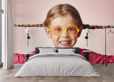 Cute smiling child wearing drawn yellow eyeglasses, holding her pigtails in happiness. Vision concept.  Wall mural