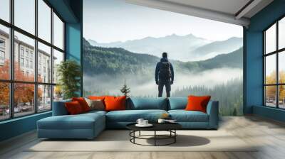 A lonely man enjoys the view of the summer mountains while he standing on a mountain peak. Hiking and digital detox concept. Contemplation of nature alone with your thoughts. Format photo 5:2. Wall mural