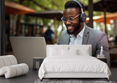 A smiley young African American man in front of laptop monitor in headphones during online video call. Wall mural