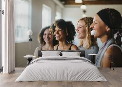 Happy friends from yoga class meet in yoga studio. Joyful young women talk sitting around wooden table in restaurant. Fitness club members plan future activity on dinner in cafeteria Wall mural