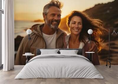 Loving middle aged couple during outdoor walking on the evening beach during sunset Wall mural