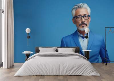 Portrait of a serious grey haired Asian middle aged businessman in a blue suit. Photo with copy space on blue background. Wall mural