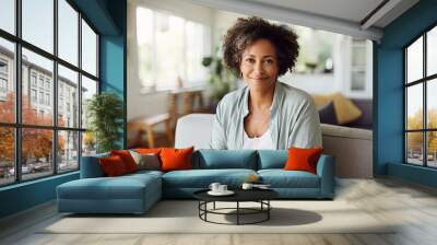 Psychological portrait of a peaceful middle-aged African American woman. She sits at home in a comfortable position. She is confident and happy. Wall mural