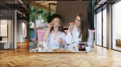 two young woman eating pizza in summer cafe Wall mural