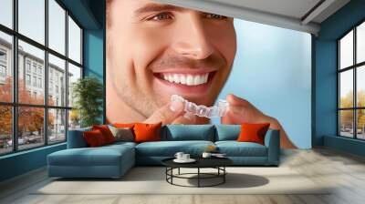 Young Caucasian man inserting a dental aligner. Close-up view. Making strides towards a stunning, aligned smile. Wall mural