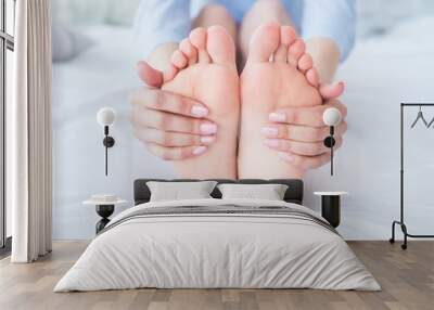 Young woman massaging her foot on the bed., Healthcare concept. Wall mural