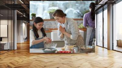 Happy adorable little child girl in apron enjoying cooking homemade pastry together with family at home. Wall mural