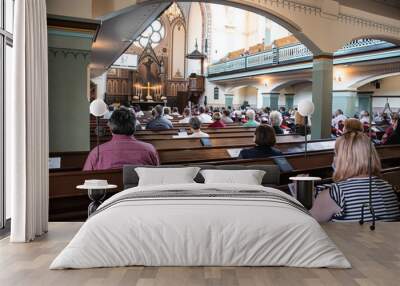 Holy mass in Christian church during the coronavirus pandemic Covid-19. Safe personal distance with protective masks Wall mural