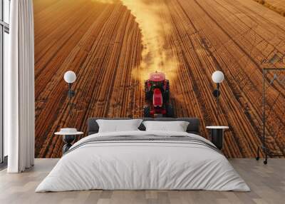 Red tractor plowing a vast dusty field Wall mural