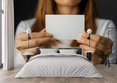 Close-up of an empty, white mock-up, banner business card in the hands of a young adult woman, female holding a small cardboard billboard for advertisements or messages with empty space, business. Wall mural