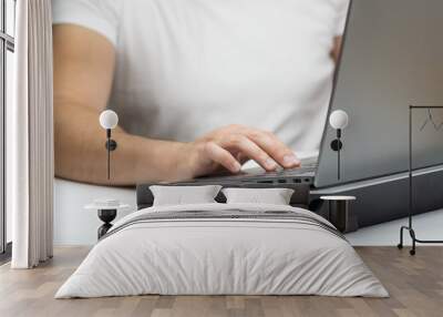 Close up of young man working on laptop on a cooling stand Wall mural