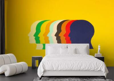 colorful paper heads looking at one point on a yellow background, all the power of the mind focused on solving problems Wall mural