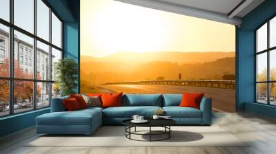 Sunset on the road. Various shades of orange in the mountains and cars passing by on the highway.. Wall mural