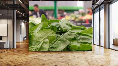 Pile of fresh green chard leaves on the marketplace counter in Belgrade. Blurred sellers and customers on background Wall mural