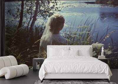 Tranquil scene displaying a bride in wedding dress gazing over a lake Wall mural