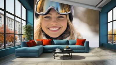 Young smiling happy cheerful Caucasian blonde woman, female skier with ski goggles and jacket on top of snowy mountain, skiing winter season, holiday and travel, extreme sports adventure, vacation. Wall mural