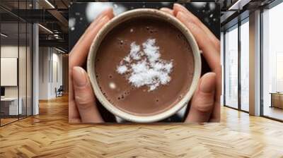 A woman holding a hot cup of coffee with both hands and warming herself on a snowy winter day. Wall mural