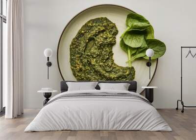 A close-up shot of a plate with a spinach sauce Wall mural