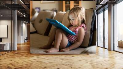 Preschool girl using a tablet computer at home Wall mural