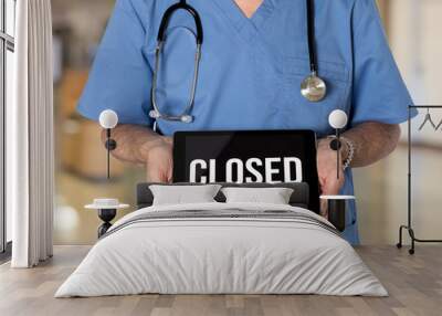 Senior male caucasian doctor with stethoscope in medical scrubs holding electronic tablet for saying hospital is closed due to coronavirus Wall mural