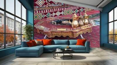 Traditional arabic coffee jugs or qahwa in Dubai with table and couch on oriental carpet with hot coals Wall mural