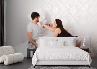 Junges Paar macht eine Kissenschlacht im Bett Wall mural