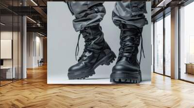 A person is wearing black boots and grey pants Wall mural