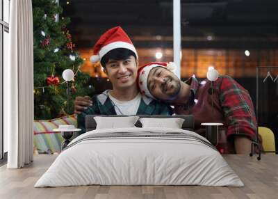 Adorable smiling young LGBT couple sharing special moment together on Christmas holiday, Asian gay male lover sitting on sofa in living room to celebrate night before Christmas, they look at camera. Wall mural