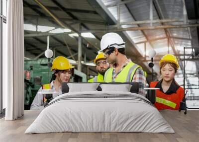 Group of industrial foreman engineer and workers with helmet and safety vest walking past to inspect machinery engine and production process at manufacturing industry factory. Teamwork at workplace Wall mural