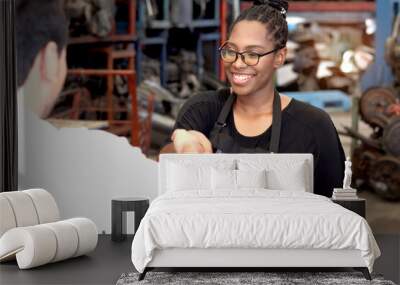 Happy African American woman staff with apron making handshake with customer after completing business deal at auto spare parts store warehouse with secondhand engine parts. Owner offer deal to buyer. Wall mural