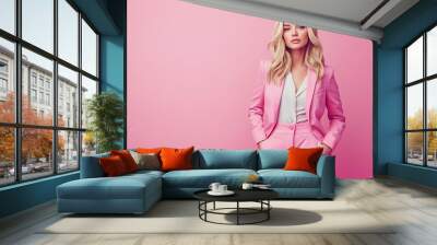 Elegant blond woman in pink clothing stands against a solid pink background with copy space. Studio. Isolated pink background. Business office elegance formal fashion style concept  Wall mural