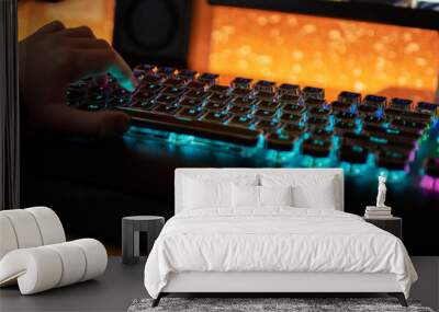 Hands of gamer man playing video games on computer in dark room using backlit colorful keyboard Wall mural