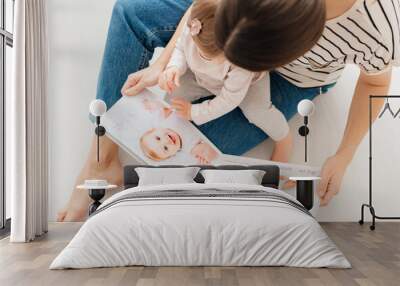 mother and daughter watch photobook from discharge of newborn baby.family tradition of printing photos and looking at them with children and remembering. Wall mural