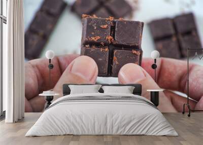 Man holding homemade dark chocolate in his hands. Wall mural