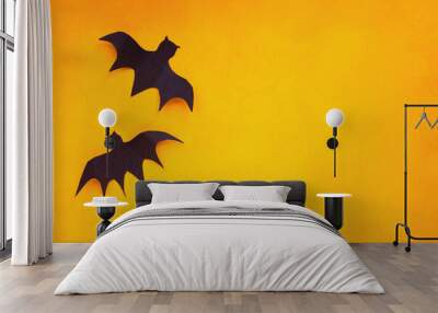 Halloween holiday decorations of two paper bats flying over an empty orange background with free space for text. Wall mural