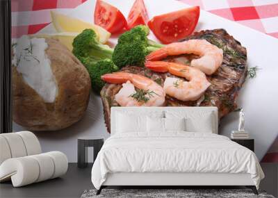 A steak and shrimp dinner over a plaid tablecloth Wall mural