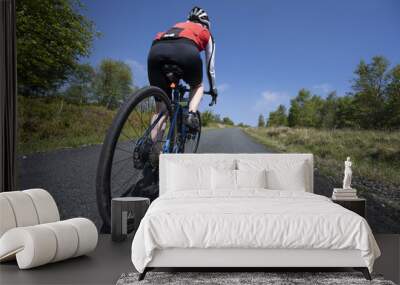 Cyclist riding the bicycle on the road under a blue sky in the United Kingdom Wall mural