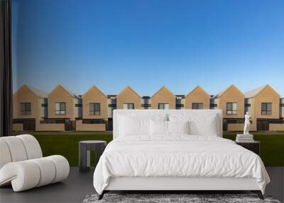 Front view of a symmetrical row of modern two storey townhouses along a footpath and lawn against a blue sky background in an Australian suburb with lots of copy space  Wall mural