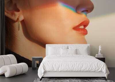 Close-up of a woman's face with a rainbow reflection on her skin, highlighting her lips and earring against a minimalist background. Wall mural