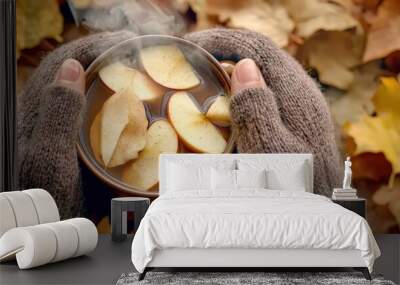 Warm drink with apple slices in cozy hands, surrounded by autumn leaves, perfect for seasonal vibes and comfort. Wall mural