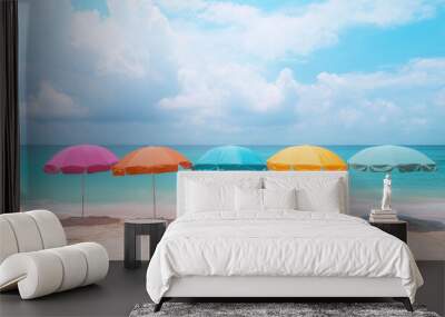 Colorful beach umbrellas on a sunny shoreline with a clear blue sky and tranquil ocean waves, creating a cheerful and relaxing summer vibe. Wall mural