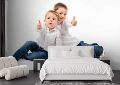 Little boys sitting on the floor giving thumbs up. Isolated on white Wall mural