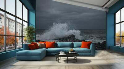 Vertical shot of a sea storm with splashing waves and rocks under a cloudy sky Wall mural