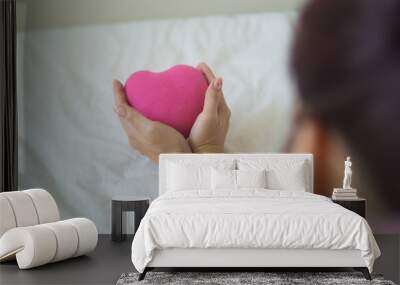 Asian woman holding a pink heart in her hands. Wall mural