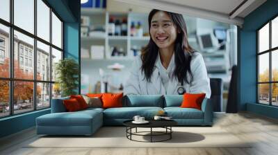 Smiling Asian young female doctor consulting online patient. Sitting at a table in a hospital office in a white coat, talking and greeting on a video call on a, Generative AI Wall mural