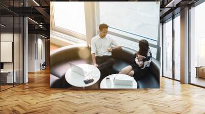 Two asian coworkers use laptop work together having coffee in afternoon Wall mural