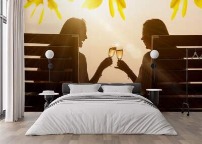 Two beautiful asian women toss white wine of champange in with warm sunset light Wall mural